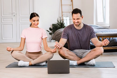couple meditate sitting at laptop